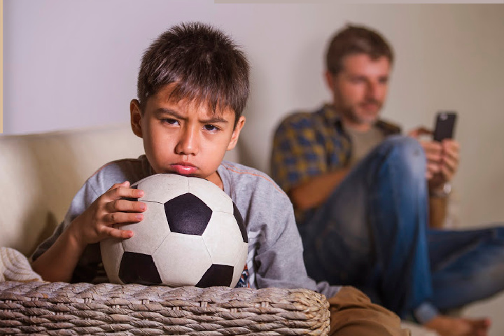 Un padre no implicado ignora a un niño con un balón de fútbol