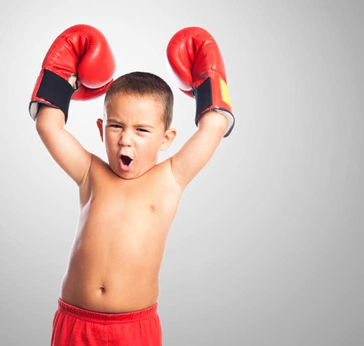 Un niño con guantes de boxeo levanta los brazos y ruge - Las palabras positivas para los niños, las palabras de aliento para los niños y las notas positivas pueden aumentar la confianza en sí mismos bien alentados
