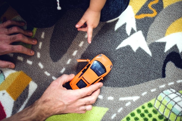 Un adulto mueve un coche de juguete mientras el niño lo señala para mejorar la inteligencia espacial visual