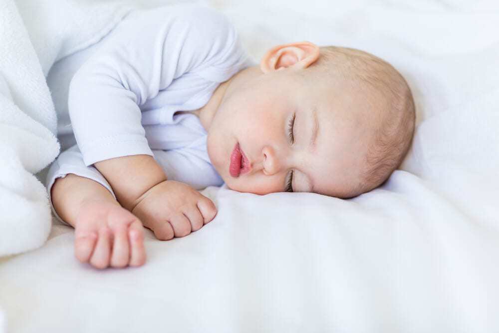 un niño de siete meses duerme con una manta