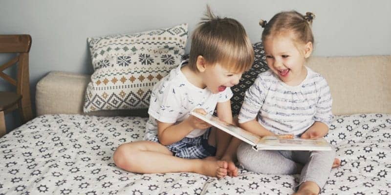 niños pequeños y niños en edad preescolar leyendo libros en la cama