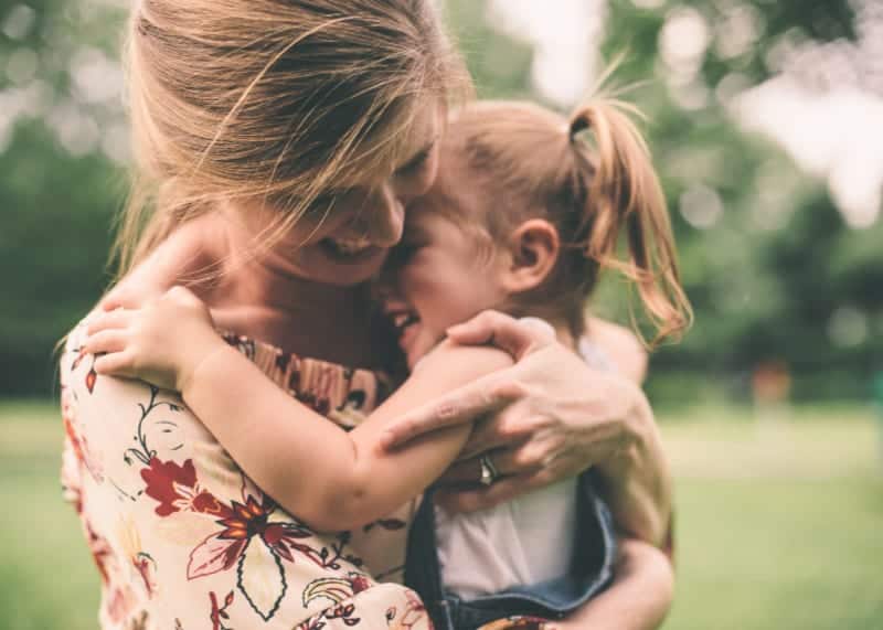cultura familiar madre abrazando a su hija al aire libre en la naturaleza