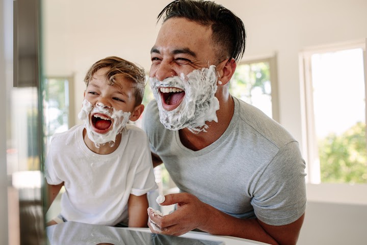 el hijo imita al padre aplicando crema de afeitar en la cara
