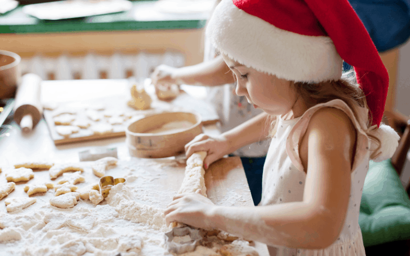 Una niña hornea galletas de su caja de Navidad.
